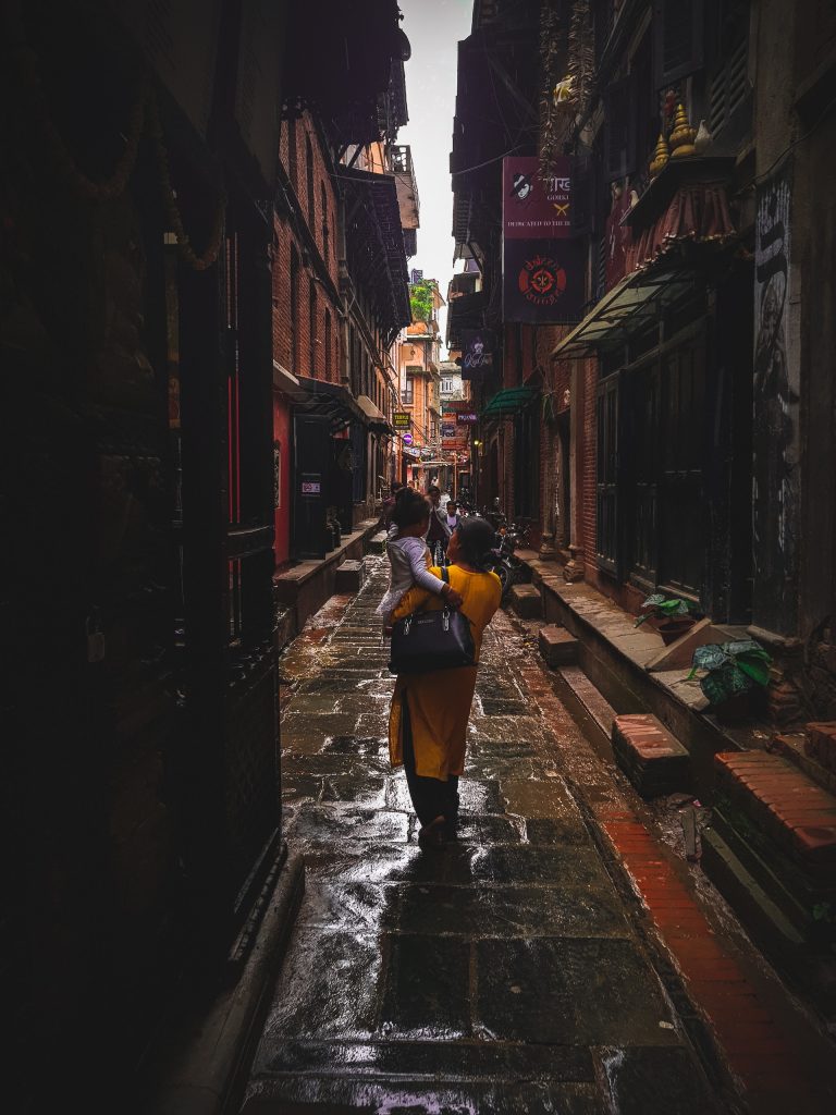 Mother holding child walking down narrow road.